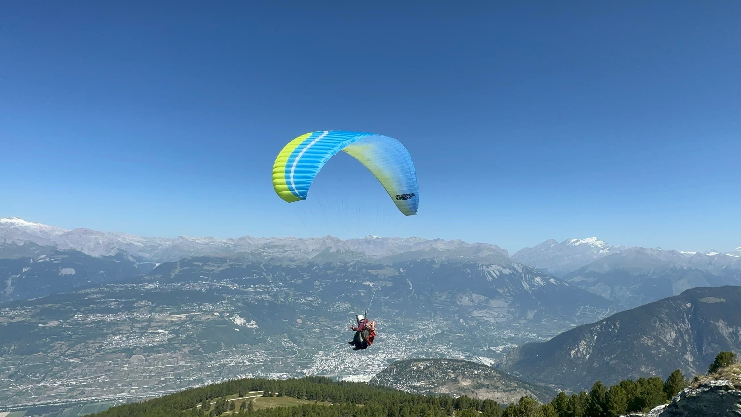 Pilote de parapente en vol au-dessus des Alpes valaisannes